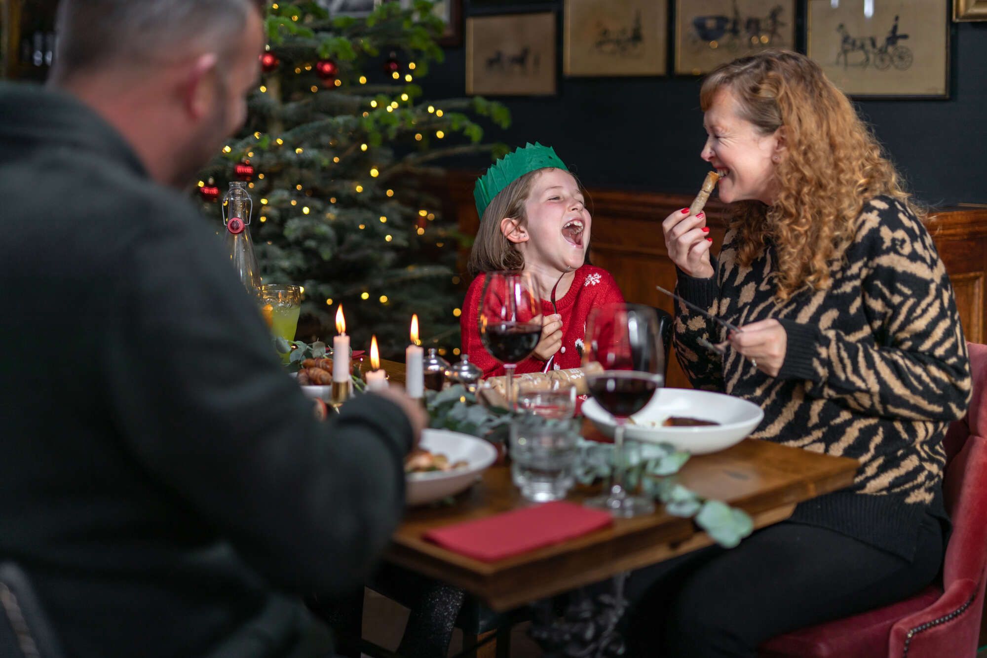 Family eating around the Christmas table with a Christmas tree in the background
