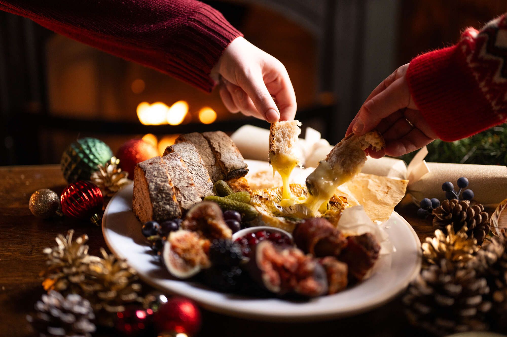 Baked Camembert being dipped with bread and being shared by the fire in the pub