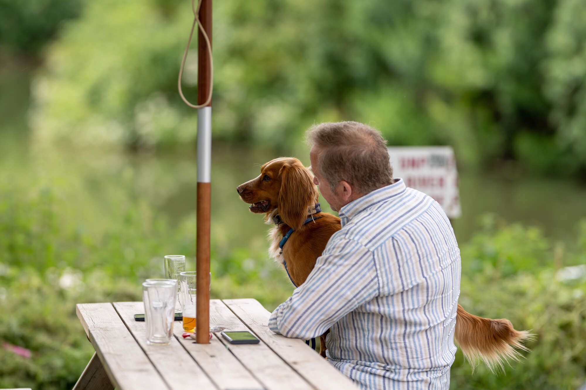 Man sat by the river Avon with his dog on the tables outside the Chequers Inn Hanham